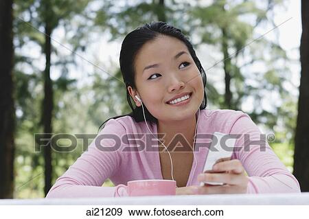 Young woman listening to MP3 player, smiling View Large Photo Image Stock Photo - Young woman listening to MP3 player, smiling. Fotosearch