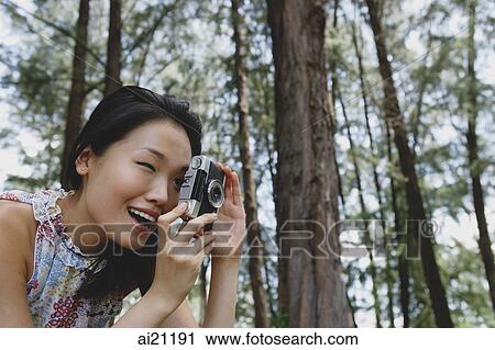 Young woman outdoors, taking a photograph View Large Photo Image Stock Image - Young woman outdoors, taking a photograph. Fotosearch