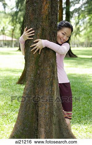 Young woman with arms around a tree View Large Photo Image Stock Photograph - Young woman with arms around a tree. Fotosearch