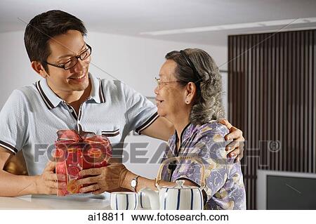 Adult offspring giving gift to senior woman View Large Photo Image Stock Image - Adult offspring giving gift to senior woman. Fotosearch