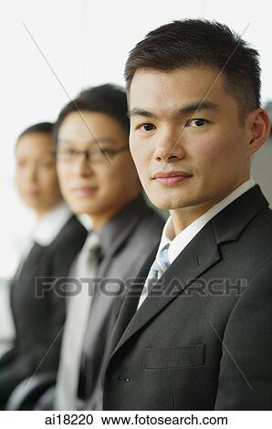 Stock Image - Business people in a row, focus on the businessman in foreground. Fotosearch