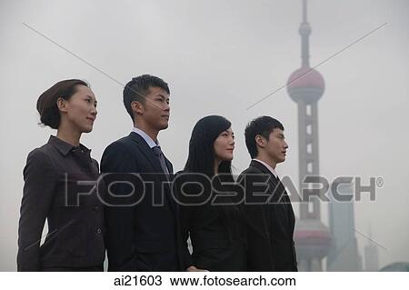 Stock Image - Business people standing in a row, looking away, Oriental Pearl TV Tower in the background. Fotosearch