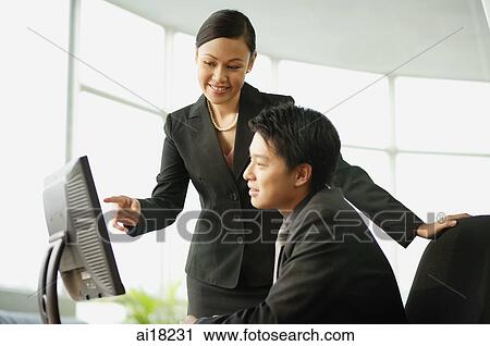 Stock Image - Businessman and businesswoman looking at computer. Fotosearch