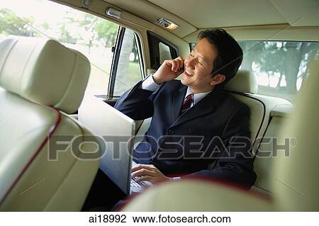 Businessman in backseat of car, using laptop and mobile phone View Large Photo Image Stock Image - Businessman in backseat of car, using laptop and mobile phone. Fotosearch