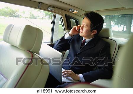 Businessman in car, using laptop and mobile phone View Large Photo Image Stock Image - Businessman in car, using laptop and mobile phone. Fotosearch