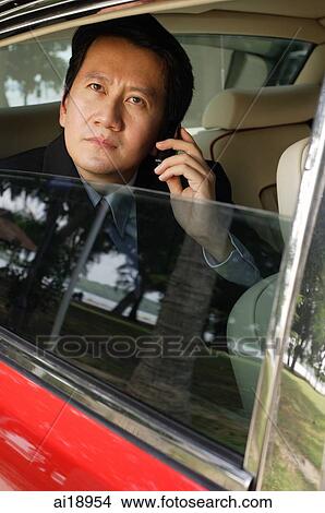 Businessman in car, using mobile phone, looking through the window View Large Photo Image Picture - Businessman in car, using mobile phone, looking through the window. Fotosearch