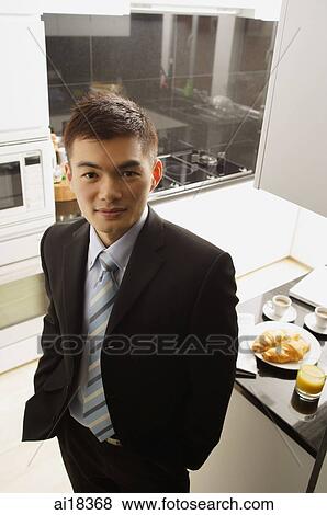Businessman in kitchen, looking up at camera View Large Photo Image Stock Photo - Businessman in kitchen, looking up at camera. Fotosearch