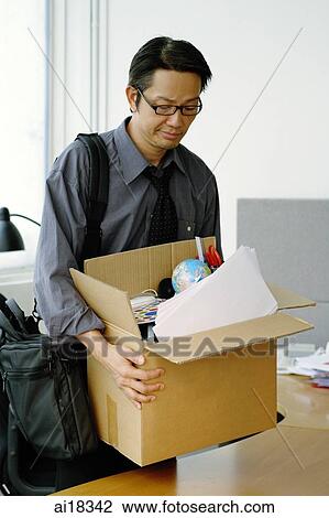 Businessman in office carrying box, grimacing, looking down View Large Photo Image Stock Image - Businessman in office carrying box, grimacing, looking down. Fotosearch