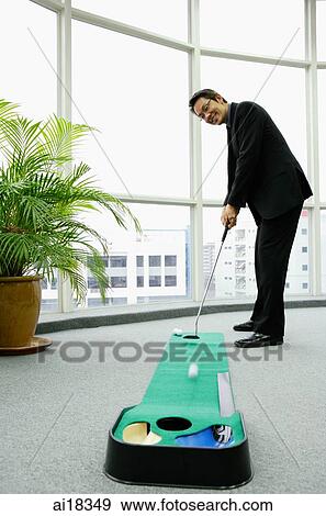 Stock Photo - Businessman in office playing golf. Fotosearch