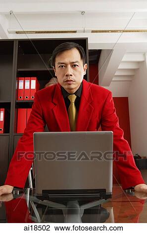 Businessman in red jacket leaning on table, laptop open in front of him View Large Photo Image Stock Image - Businessman in red jacket leaning on table, laptop open in front of him. Fotosearch