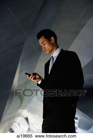 Businessman in tunnel, looking at mobile phone View Large Photo Image Stock Photography - Businessman in tunnel, looking at mobile phone. Fotosearch