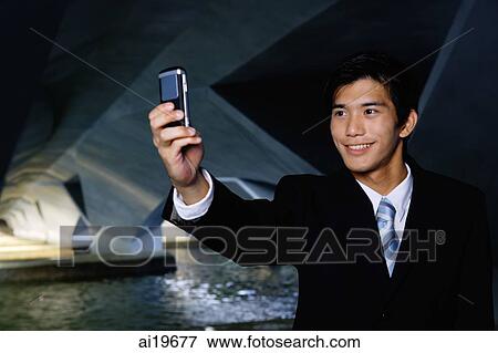 Businessman in tunnel, taking a picture of himself with camera phone View Large Photo Image Stock Photo - Businessman in tunnel, taking a picture of himself with camera phone. Fotosearch