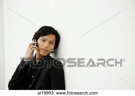 Businessman leaning on wall, using mobile phone View Large Photo Image Stock Image - Businessman leaning on wall, using mobile phone. Fotosearch