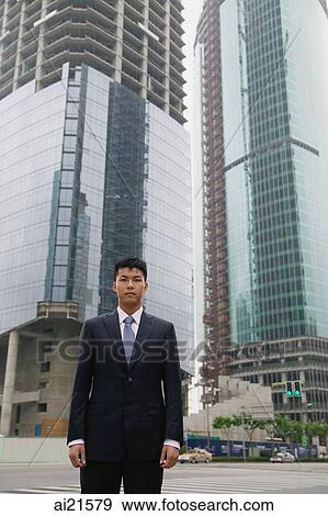 Businessman looking at camera, building under construction behind him View Large Photo Image Stock Photo - Businessman looking at camera, building under construction behind him. Fotosearch