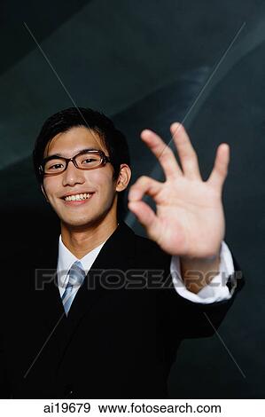 Businessman looking at camera, making hand sign View Large Photo Image Stock Photo - Businessman looking at camera, making hand sign. Fotosearch