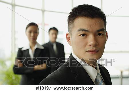 Businessman looking at camera, people in the background View Large Photo Image Stock Photo - Businessman looking at camera, people in the background. Fotosearch