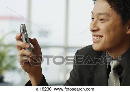 Businessman looking at mobile phone View Large Photo Image Stock Image - Businessman looking at mobile phone. Fotosearch