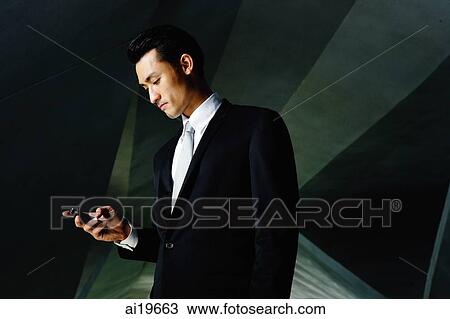 Businessman looking at mobile phone View Large Photo Image Stock Image - Businessman looking at mobile phone. Fotosearch