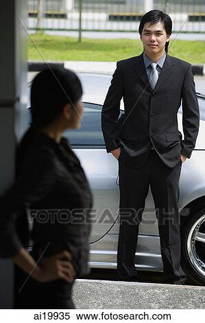 Businessman looking at woman standing in foreground View Large Photo Image Stock Photography - Businessman looking at woman standing in foreground. Fotosearch