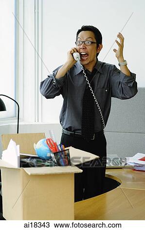 Businessman on phone in office, shouting, box full of items on top of desk View Large Photo Image Stock Image - Businessman on phone in office, shouting, box full of items on top of desk. Fotosearch