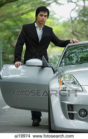 Picture - Businessman opening car door, looking at camera. Fotosearch