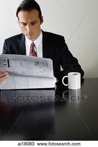 Businessman sitting at table reading newspaper, mug on table next to him View Large Photo Image Stock Image - Businessman sitting at table reading newspaper, mug on table next to him. Fotosearch