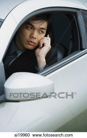 Stock Image - Businessman sitting in car, using mobile phone. Fotosearch