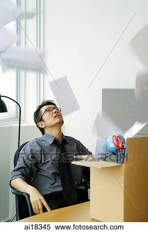 Businessman sitting in office, papers falling around him View Large Photo Image Stock Photography - Businessman sitting in office, papers falling around him. Fotosearch