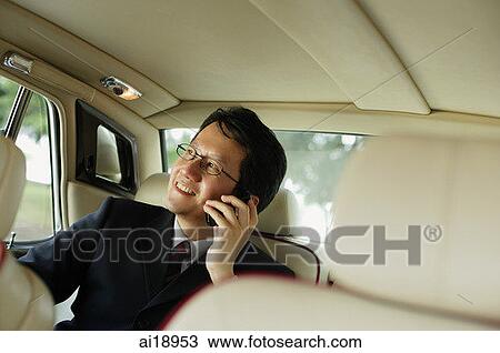 Businessman sitting inside car, using mobile phone View Large Photo Image Stock Image - Businessman sitting inside car, using mobile phone. Fotosearch