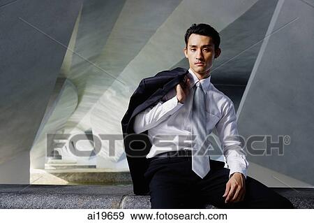 Stock Photo - Businessman sitting on ledge, holding jacket over shoulder, looking at camera. Fotosearch