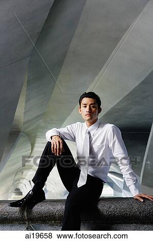 Businessman sitting on ledge, looking at camera View Large Photo Image Stock Photo - Businessman sitting on ledge, looking at camera. Fotosearch