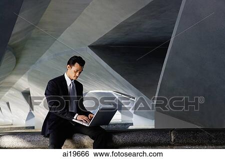 Businessman sitting on ledge, using laptop View Large Photo Image Stock Photograph - Businessman sitting on ledge, using laptop. Fotosearch