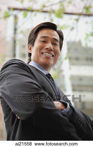 Stock Photo - Businessman standing in the city, arms crossed, smiling. Fotosearch