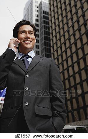 Businessman standing in the city using mobile phone View Large Photo Image Stock Photo - Businessman standing in the city using mobile phone. Fotosearch
