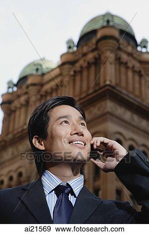 Businessman standing in the city using mobile phone View Large Photo Image Stock Photo - Businessman standing in the city using mobile phone. Fotosearch
