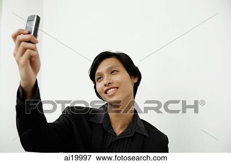 Stock Photo - Businessman using camera phone, taking a picture. Fotosearch
