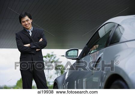 Stock Photo - Businessman with arms crossed, standing next to car. Fotosearch