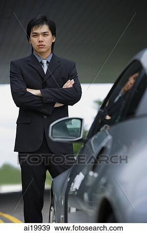 Businessman with arms crossed, standing next to car, portrait View Large Photo Image Stock Photo - Businessman with arms crossed, standing next to car, portrait. Fotosearch