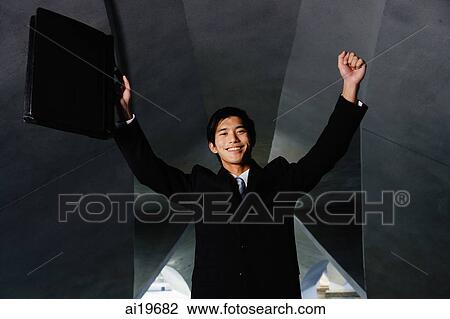 Businessman with arms raised, holding briefcase View Large Photo Image Stock Image - Businessman with arms raised, holding briefcase. Fotosearch