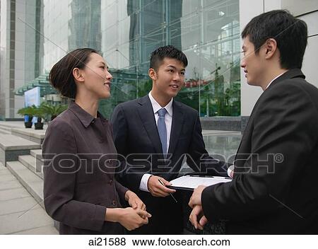 Stock Photo - Businessmen and businesswoman outside a building, talking. Fotosearch