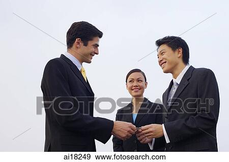 Businessmen exchanging business cards, businesswoman in the background View Large Photo Image Stock Photo - Businessmen exchanging business cards, businesswoman in the background. Fotosearch