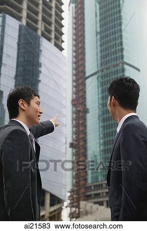 Businessmen in the city, looking at buildings in the background View Large Photo Image Stock Image - Businessmen in the city, looking at buildings in the background. Fotosearch