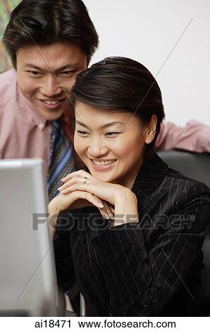 Businesspeople, side by side, looking at laptop View Large Photo Image Stock Image - Businesspeople, side by side, looking at laptop. Fotosearch