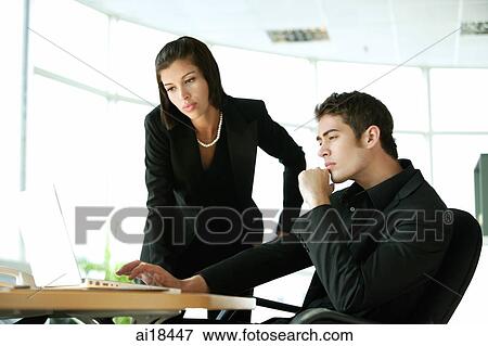 Stock Photo - Businesswoman and businessman looking at laptop. Fotosearch