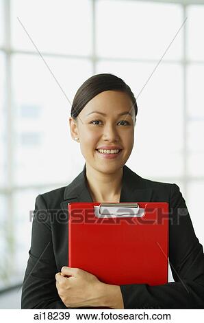 Businesswoman carrying file, smiling at camera View Large Photo Image Stock Photo - Businesswoman carrying file, smiling at camera. Fotosearch