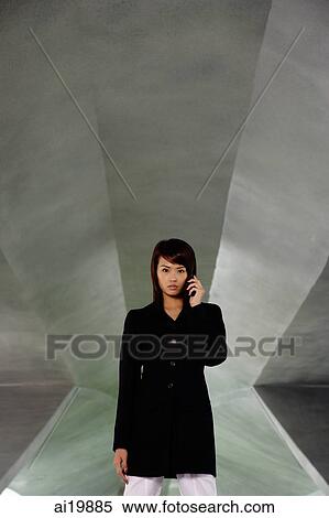 Stock Photography - Businesswoman in black jacket, using mobile phone. Fotosearch