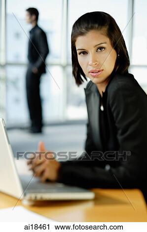Businesswoman in front of laptop, man in the background View Large Photo Image Stock Image - Businesswoman in front of laptop, man in the background. Fotosearch