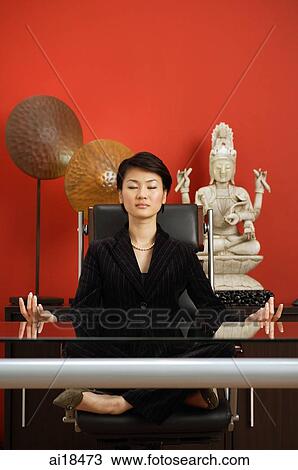 Businesswoman in office, sitting cross-legged on chair, meditating View Large Photo Image Stock Image - Businesswoman in office, sitting cross-legged on chair, meditating. Fotosearch