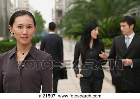 Businesswoman looking at camera, people in the background View Large Photo Image Stock Photo - Businesswoman looking at camera, people in the background. Fotosearch