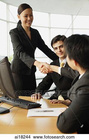 Businesswoman shaking hands on seated businessman in office View Large Photo Image Picture - Businesswoman shaking hands on seated businessman in office. Fotosearch